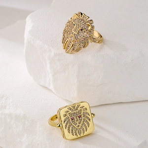 Gold plated lion head rings with zircon stones on white stone display