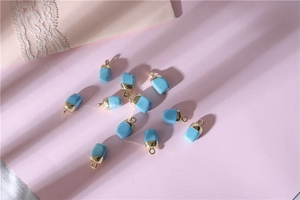 Macro view of blue turquoise stone pendants with gold metal caps on pink background