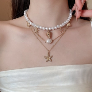 Close-up of layered beach necklace with starfish, seashell pendants and white pearls