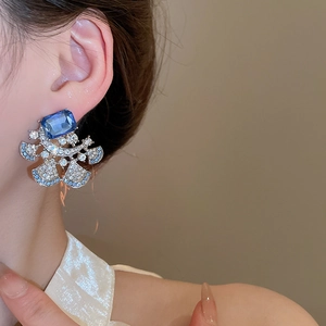Detailed view of luxury vintage floral earrings with deep blue gemstones on a model