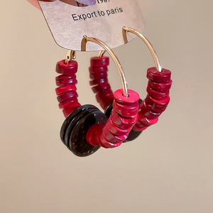 Détail de créoles bohèmes avec perles de bois vintage et disques de noix de coco