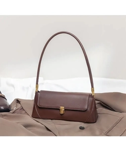 Detail of a brown baguette shoulder bag with a sleek golden metal buckle closure