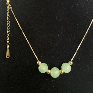 Detail of gold-plated stainless steel chain necklace with green cat-eye stone beads