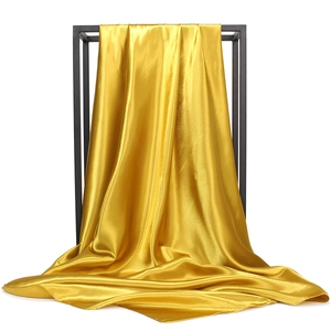 Detailed view of golden satin fabric hanging on a rack showing smooth silk texture