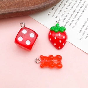 Detail of red resin charms featuring strawberry, gummy bear, and dice with metal rings
