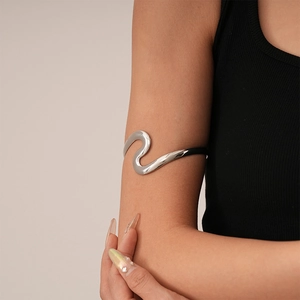 Polished silver wavy arm cuff showing a minimalist curved design on a female model arm