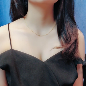 Gros plan d'un collier ras du cou à billes dorées porté par un mannequin sur fond noir