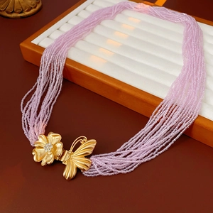Detail of pink beaded multi-layer necklace with gold butterfly and floral rhinestone clasp