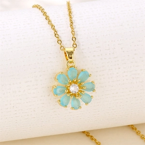Golden sunflower necklace with blue teardrop zircon petals on white textured background