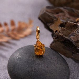 Detailed view of an S925 silver pear-shaped yellow gemstone pendant on a rustic rock