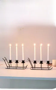 Detail of black metal sleigh candle holder with white spiral candles for festive decor