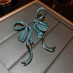 Detail of luxury bow-shaped tassel earrings with sky blue rhinestones on gun black metal
