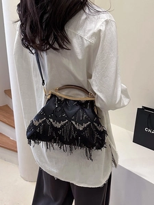 Vintage black shell bag with sequins and tassels shown by model for a stylish look