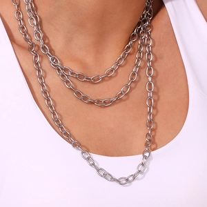 Macro detail of minimalist layered silver stainless steel cross chain necklace on a model