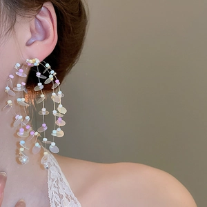 Detail of colorful round sequins and transparent thread on beaded hoop earrings