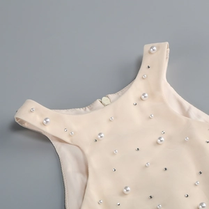 Detail of beaded halter neckline with pearls and rhinestones on apricot dress