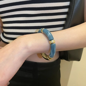 Vue détaillée d'un bracelet en perles acryliques bleues et intercalaires dorés au poignet