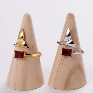 Minimalist fishtail open rings in gold and silver with red gemstone on wooden stands