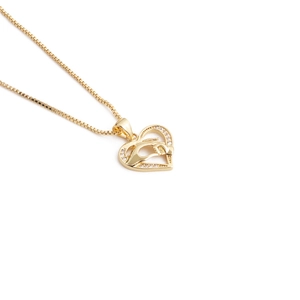 Close-up of golden heart pendant with hand-in-hand relief and sparkling zircon inlay