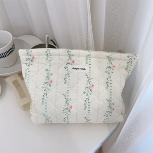 Detail of cream floral quilted makeup bag with zipper and simple wish label