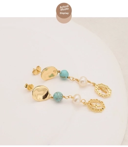 Détail de boucles d'oreilles dorées 18k avec perles d'eau douce et pendentifs croix