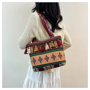 Bohemian woven tote bag featuring geometric patterns, earthy tones, and tassel fringe
