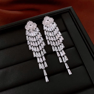 Macro shot of silver tassel earrings with sparkling zircons on a black jewelry display