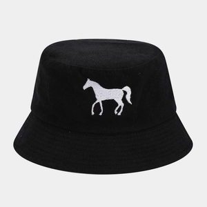 Detailed view of white horse embroidery on black corduroy fabric of a bucket hat