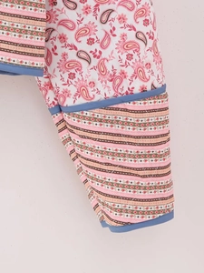 Detail of pink quilted jacket featuring floral prints and geometric stripe borders