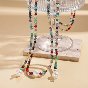 Detail of colorful faceted glass beads and large faux pearl on a long layered necklace