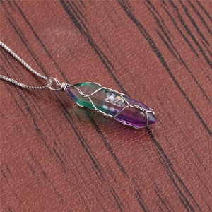 Detailed shot of green and purple gradient crystal pendant wrapped in silver wire