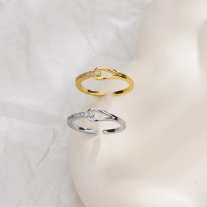 Detail of adjustable knotted rings in gold and silver with zircon accents on hand