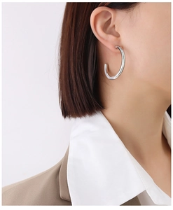 Polished silver hollow C-shaped hoop earrings on female model in natural light