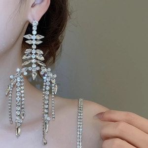 Detailed close-up of sparkling silver tassel earrings with crystal rhinestones on a model