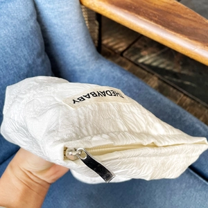 Close-up of white rose jacquard canvas makeup bag with silver zipper and brand tag
