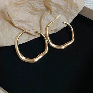 Detail of gold irregular twisted hoop earrings with polished finish on black velvet base