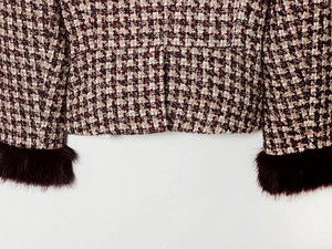 Detailed macro view of tweed jacket with burgundy faux fur cuffs and plaid pattern