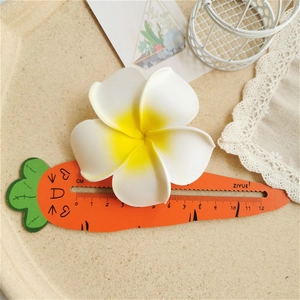 Detail showing white and yellow frangipani hair clip with size reference around 8cm