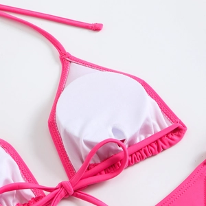 Detail of pink bikini top with ruffled edges and removable padding on white background