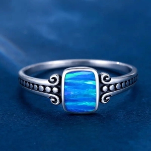 Macro detail of vintage silver ring with rectangular blue opal stone and scroll embossing