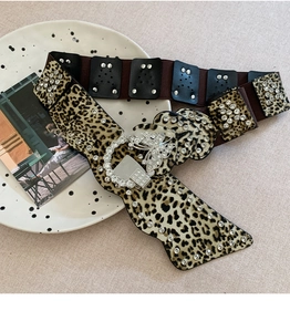 Détail d'une ceinture léopard avec une boucle ronde ornée d'un papillon en strass brillant