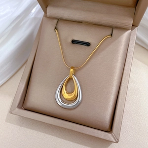 Detail of two-tone teardrop pendant necklace in a beige velvet jewelry box display