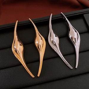 Detailed view of curved teardrop earrings in polished gold and silver finishes