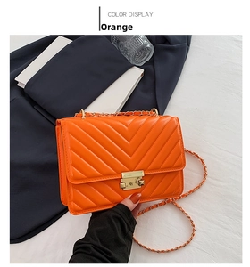 Detail showing the orange V-quilted leather crossbody bag with metal twist lock closure