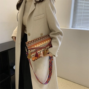 Close-up of bohemian knit crossbody bag with vibrant tassels and wide patterned strap