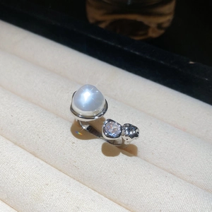 Macro shot of a multilayered silver ring with a large white pearl and zircon stones