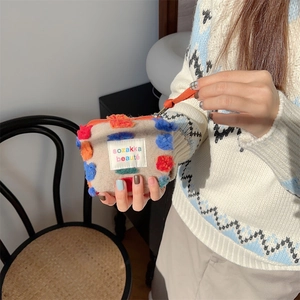 Dettaglio della borsa per trucco in feltro grigio con pompon colorati e zip arancione