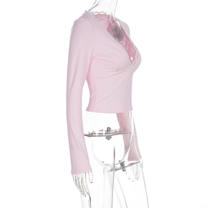 Detail of pink long-sleeve crop top with delicate white lace trim on the V-neckline