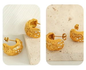 Detail of 18k gold C-shaped earrings featuring star and moon relief with zircon stones