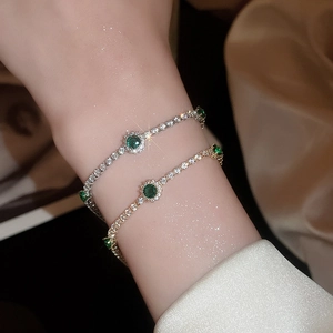 Gros plan de bracelets élégants en or et argent avec pierres vert émeraude et diamants